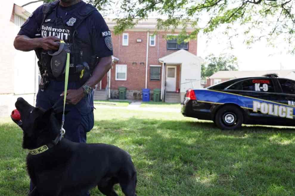 BALTIMORE, MARYLAND - JULY 03: An officer of the Baltimore Police Department and his K-9 are seen at the crime scene of a mass shooting in the Brooklyn Homes neighborhood on July 3, 2023 in Baltimore, Maryland. Two people were killed and dozens injured, many of them minors, during a mass shooting at a block party in the South Baltimore neighborhood.